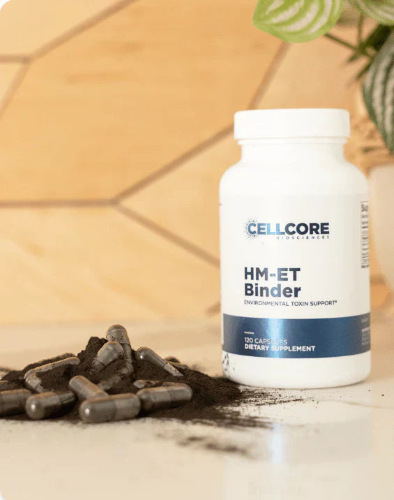 CellCore HM-ET Binder supplement bottle with open capsules and black powder on a counter, symbolizing deep environmental toxin support and powerful binding capacity.